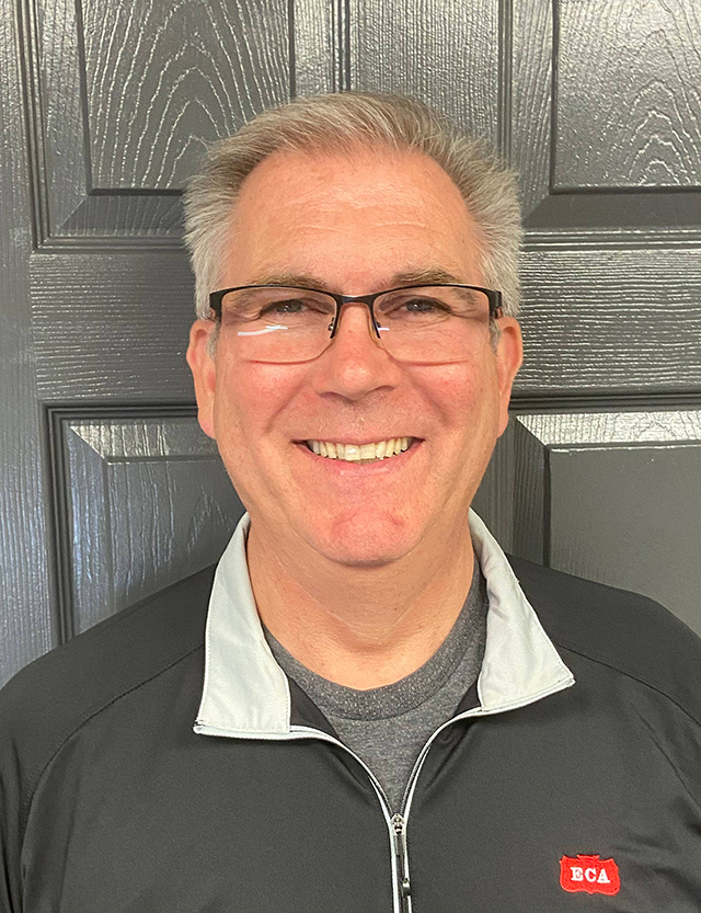 man with gray hair smiling in front of a door