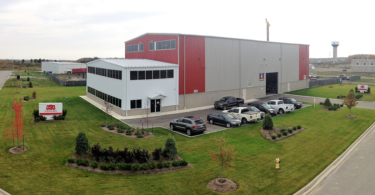 view of a large warehouse building surrounded by a small parking lot and grass