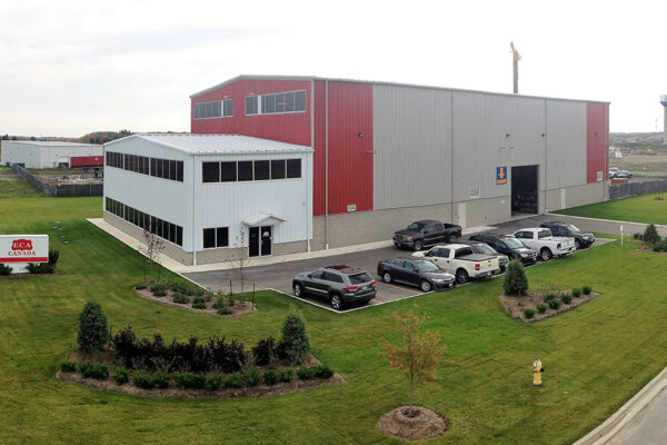 view of a large warehouse building surrounded by a small parking lot and grass