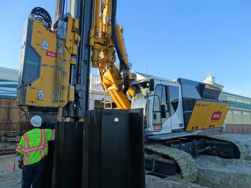 Workers drive piles next to boardwalk